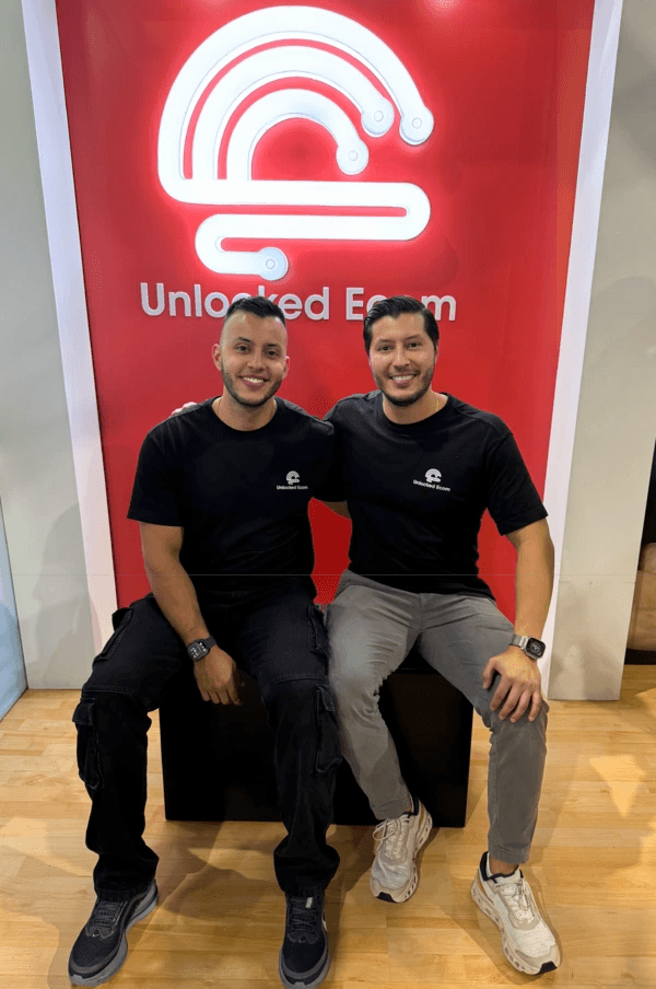 Jose y Juan Naicipa, hermanos fundadores de Unlocked, frente al backdrop rojo de la marca.